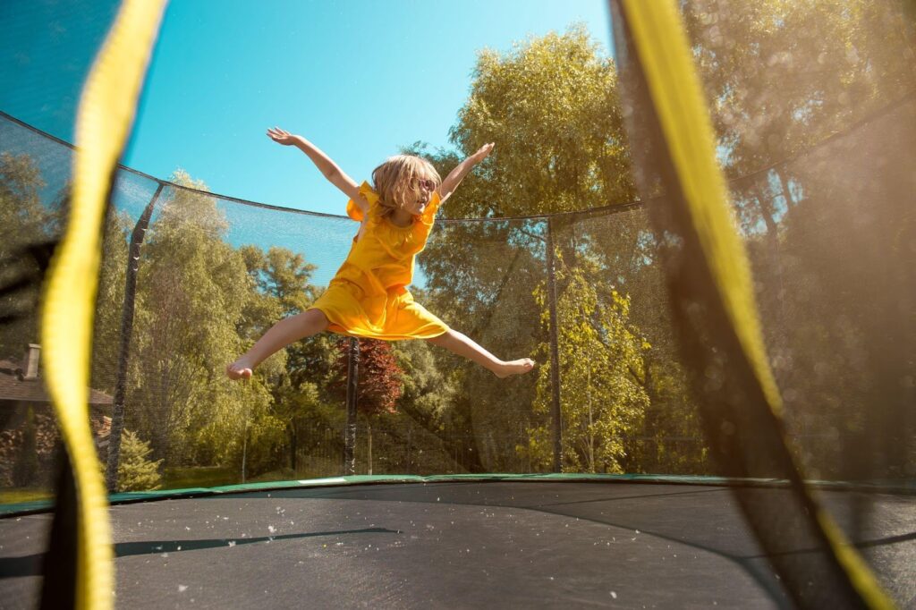 Dítě skáče na trampolíně venku za slunečného dne