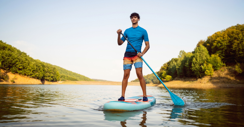 Osoba pádluje na paddleboardu po klidném jezeře