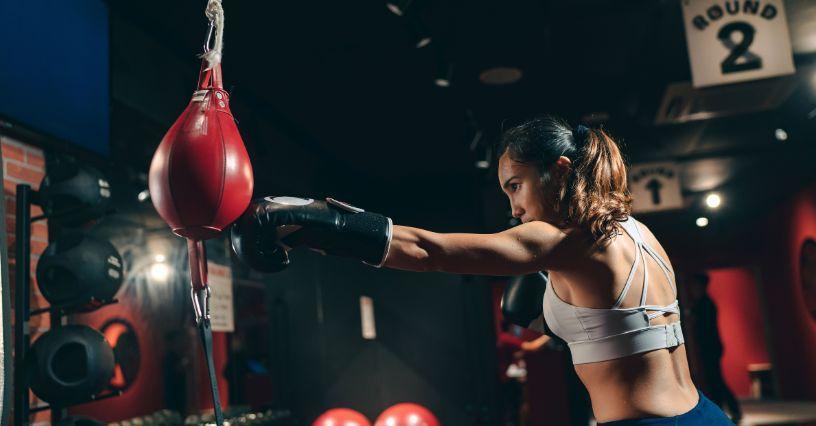 Boxerka používá boxovací pytel ve fitness centru
