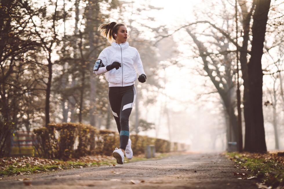 Žena v sportovním oblečení běhá v parku za podzimního dne