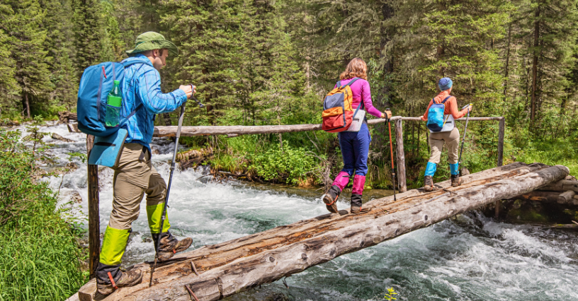 Turisté používají trekkingové hole a batohy při přechodu přes most